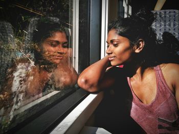 Thoughtful young woman sitting by window at home