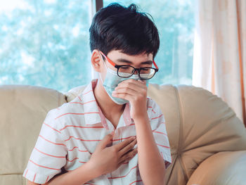 Close-up of boy wearing mask sitting on sofa