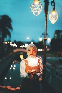 Woman looking at illuminated lamp