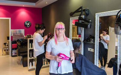 Portrait of female hairdresser standing in salon