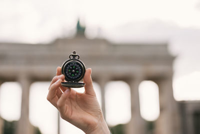 Old classic navigation compass in hand on brandemburg gate background, symbol of tourism