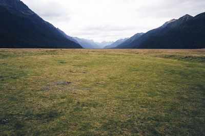 Scenic view of green landscape and mountains against sky