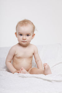 Portrait of cute baby sitting on bed at home