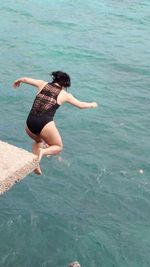 Rear view of woman jumping in sea