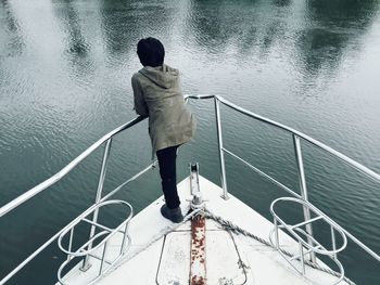 Rear view of man standing in boat at sea