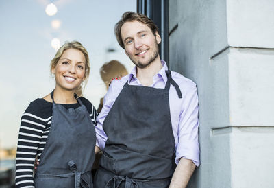 Mid adult confident owners standing at the entrance of restaurant