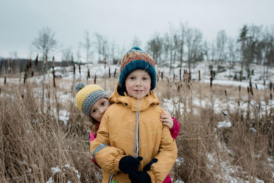 Siblings looking at the camera whilst playing outside in the snow