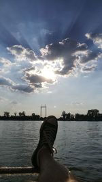 Low section of man on river against sky