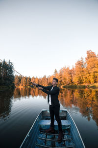 Man standing by lake against sky during autumn