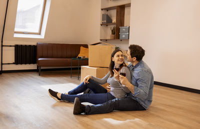 Side view of young woman sitting on bed at home