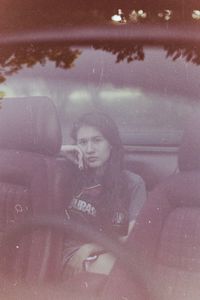 Portrait of young woman photographing in car