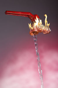 Close-up of lit candle against red background