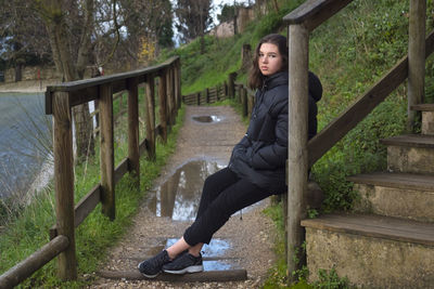 Tired teen girl sitting on a parapet in a park