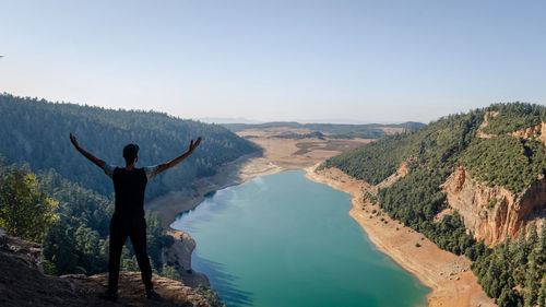 Rear view of man standing on mountain against sky