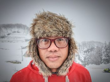 Portrait of man wearing fur hat against trees during winter