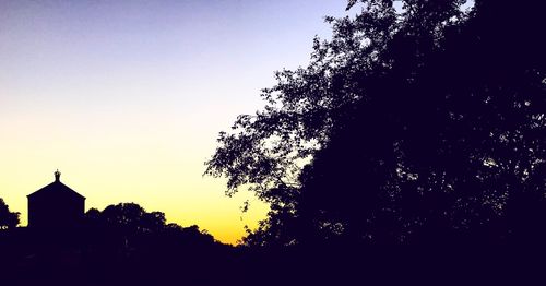 Silhouette built structures against clear sky at dusk