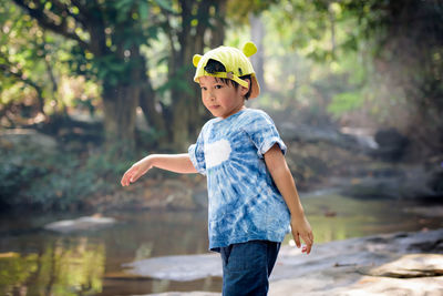 Boy wearing yellow cap walking in forest