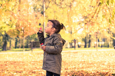 Full length of boy standing by tree during autumn