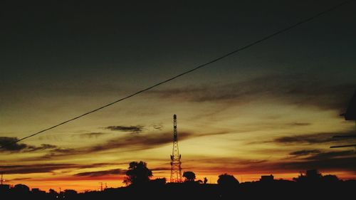 Silhouette power lines against sky during sunset