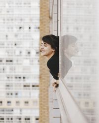 Smiling young woman looking through window