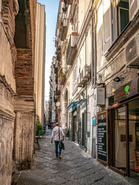 Rear view of woman walking on street amidst buildings