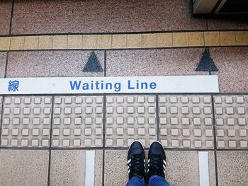 Low section of person standing on arrow sign