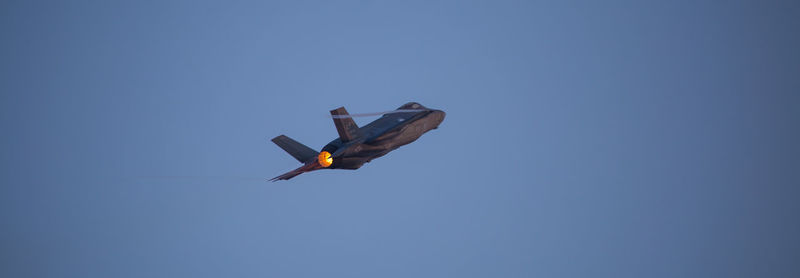 Low angle view of airplane flying against clear blue sky