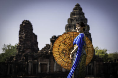 Woman in traditional clothing standing against historic building 