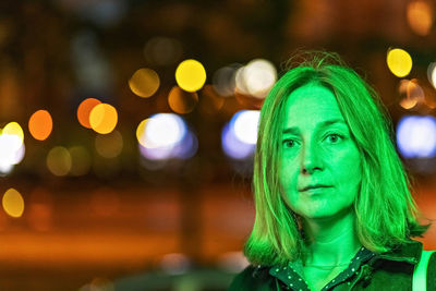 Portrait of a young woman in a night city in neon green on a summer evening. city lights.