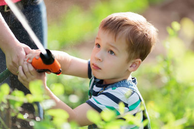 High angle view of boy spraying water in back yard