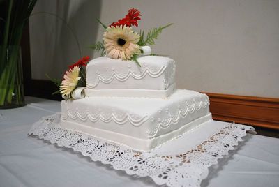 Flower over cake on table against white wall