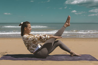 Young woman doing pilates exercise on the beach