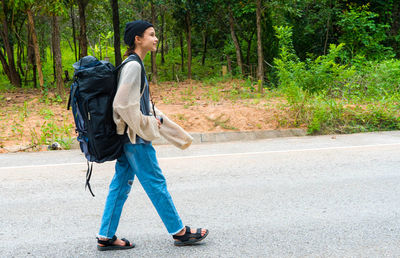 Woman traveling with backpack walking on path in tropical forest, udon thani, thailand