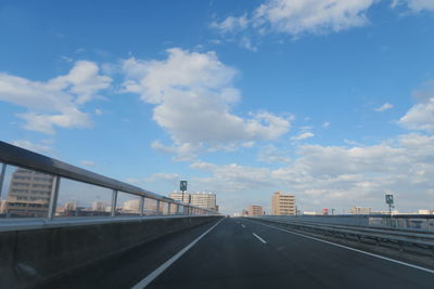 Road leading towards city against sky