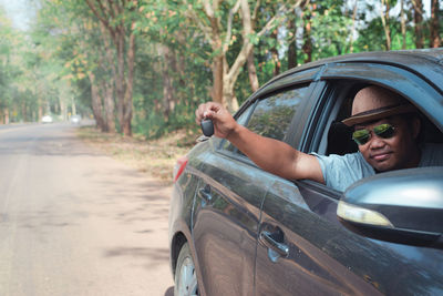 Portrait of man driving car on road