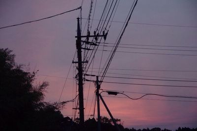 Low angle view of silhouette electricity pylon against sky