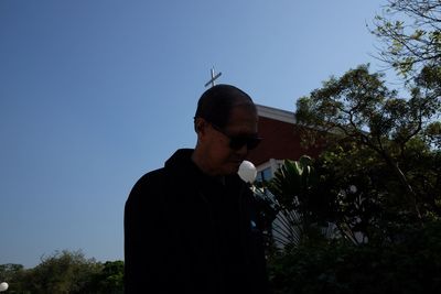 Low angle view of man standing by tree against clear sky