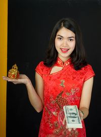 Portrait of smiling woman standing against black background