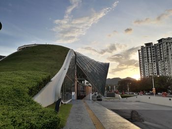 Road by buildings in city against sky