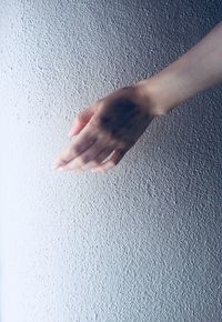 Cropped hand of woman against wall