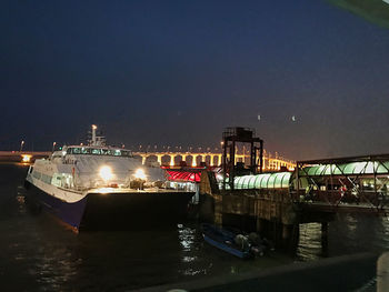 Illuminated ship moored in sea against sky at night