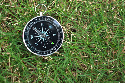 High angle view of navigational compass on grassy field