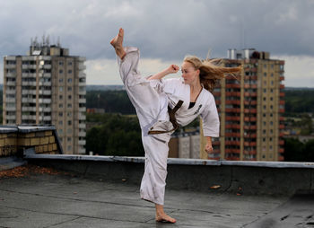 Full length of young woman standing against building