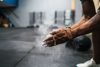 Low section of man dusting chalk powder for exercising in gym