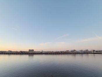 Scenic view of river by buildings against sky during sunset