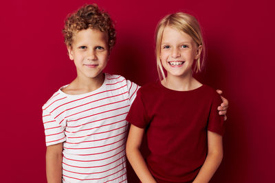 Portrait of smiling sibling against red background