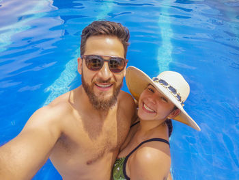 Portrait of smiling young man and woman in swimming pool