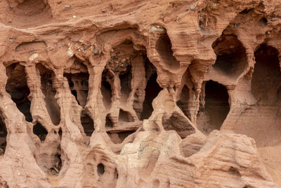 Red sandstone rocks washed out by the water with deep furrows and hollows