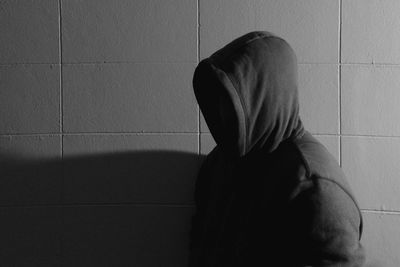 Rear view of a woman sitting against wall