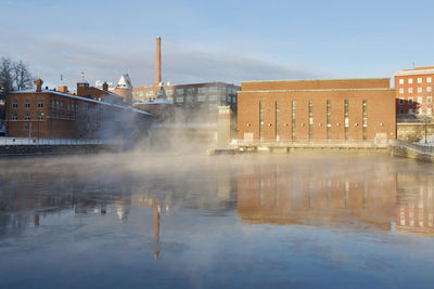 River by buildings against sky